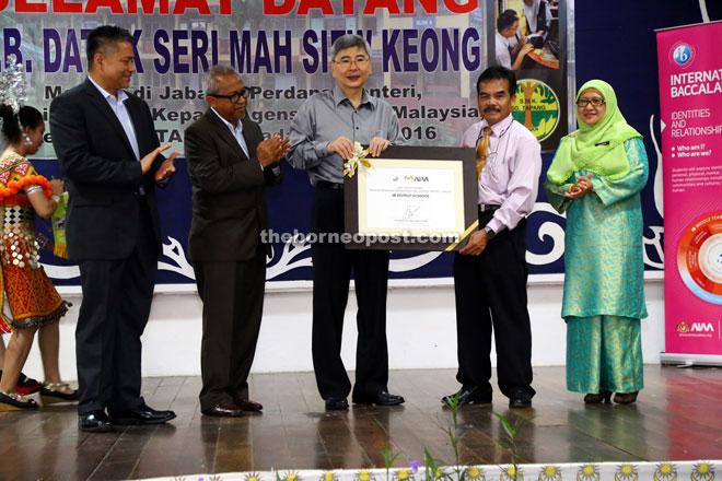 Mah (third left) presents the IB MYP recognition to the principal of SMK Sungai Tapang Bekon Jenet as others look on.